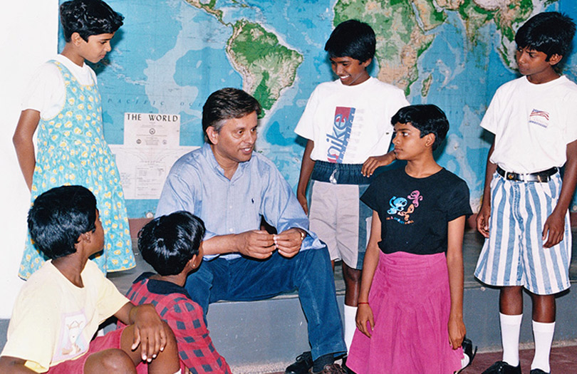Dr. Abraham George sitting with students around him