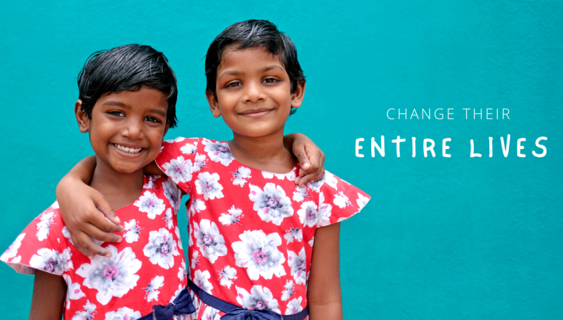 Two preschool children wearing red flowered dresses and smiling