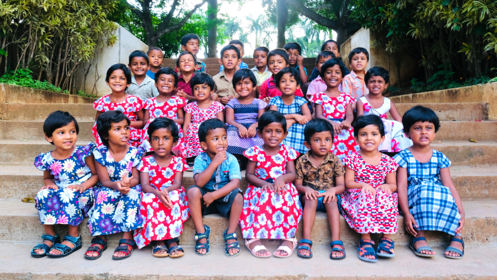 Two preschool children wearing red flowered dresses and smiling