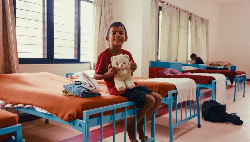 Ravi sitting on his bed. Giving Tuesday is our biggest fundraiser of the year. All funds go towards supporting children like Ravi to reach their full potential and break the cycle of poverty in one generation.